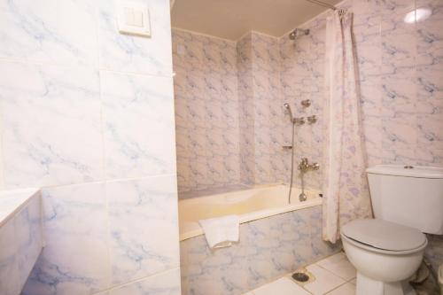 a bathroom with a toilet and a shower and a tub at Hotel The Enchanted in Dhaka