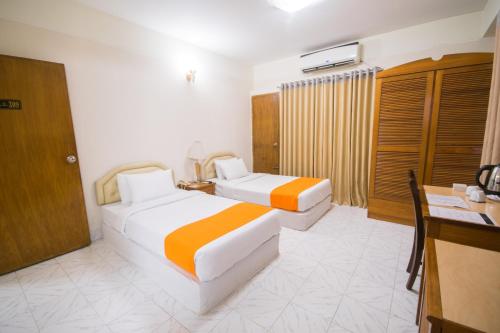 a hotel room with two beds and a desk at Hotel The Enchanted in Dhaka