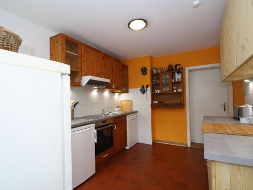 a kitchen with orange walls and white appliances at XXL Ferienhaus mit Sauna in Upost in Upost