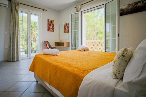 a bedroom with a large bed with a yellow blanket at Porto Gerakas Villas in Vasilikos