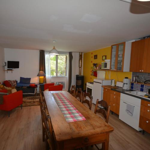 a kitchen and living room with a wooden table and chairs at Essentiel Barret in Barret-sur-Meouge