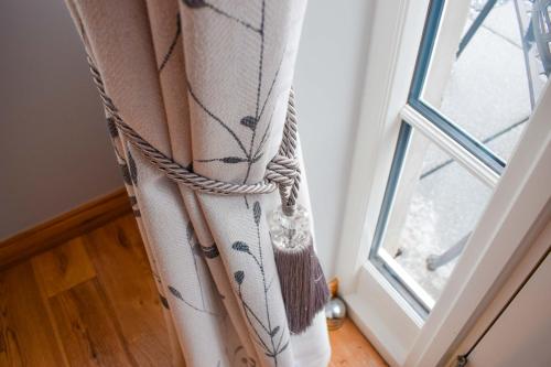 a curtain with a rope next to a window at Outlander Glencoe at Creag an-t Sionnaich Glencoe Ballachulish Highlands Near Fort William in Glencoe