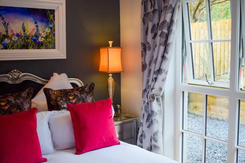 a bedroom with a bed with red pillows and a window at Outlander Glencoe at Creag an-t Sionnaich Glencoe Ballachulish Highlands Near Fort William in Glencoe