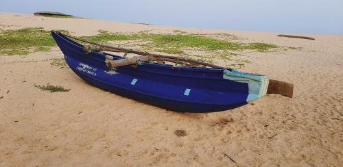 a blue boat sitting on the sand on a beach at Pearl Cave Cabanas & Resturant in Tangalle