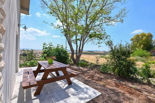 a wooden picnic table on a patio with a tree at YalaRent Valley view Boutique cottages with Pool in Merhavyāh