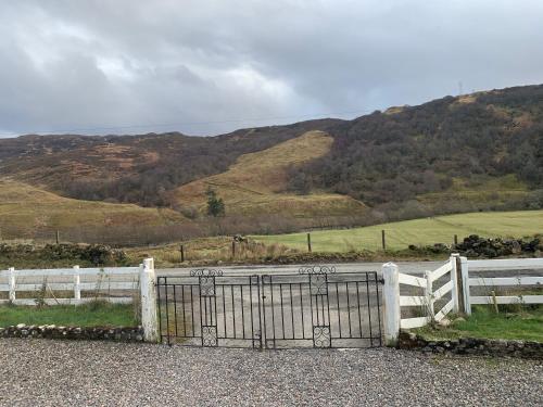 a white fence with a gate in front of a mountain at The Annex in Glenelg in Glenelg
