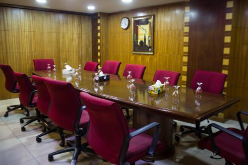 a conference room with a long table and red chairs at Hotel The Enchanted in Dhaka