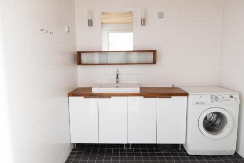a white kitchen with a sink and a washing machine at ---2ndhomes Cozy Courtyard home with Sauna in Kruununhaka--- in Helsinki