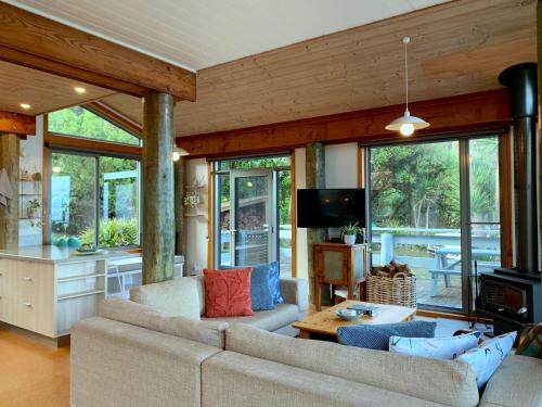 sala de estar con 2 sofás y cocina con ventanas en Surf Shack, en Wye River