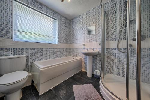 a bathroom with a toilet and a tub and a sink at Upton Village Guest House in Birkenhead