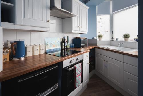 Una cocina con gabinetes blancos y una encimera de madera. en One Sandringham - Boutique Seaside Home in Ilfracombe, en Ilfracombe