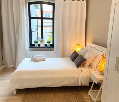 a bedroom with a large white bed with a window at Lounge Club Apartment in Gdańsk