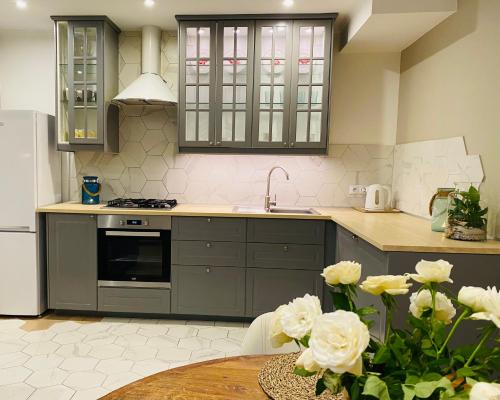 uma cozinha com armários cinzentos e uma mesa com rosas brancas em Lounge Club Apartment em Gdańsk