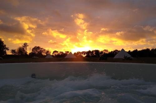 a sunset over a swimming pool with the sun setting at Cobweb Cottage in Spooner Row