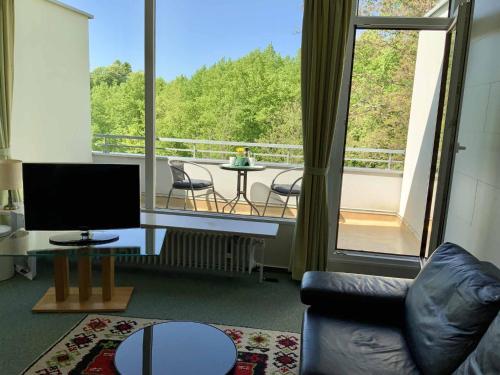 a living room with a television and a balcony at Appartement an der Helenenquelle in Bad Pyrmont