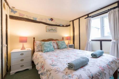 a bedroom with a bed with blue pillows and a window at Cobweb Cottage Studios in Spooner Row
