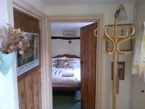a bedroom with a bed and a door leading to a room at Cobweb Cottage Studios in Spooner Row
