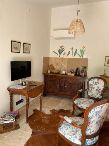 a living room with a tv and a chair and a table at Guest House Encantada in Nîmes