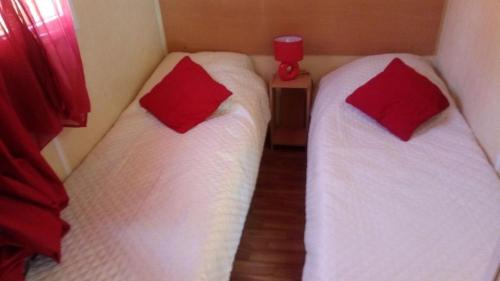 - 2 lits dans une chambre avec des oreillers rouges dans l'établissement MOBILHOME 4/5 P /GORGES DU VERDON / TOUT EQUIPE / / TOUT CONFORT / REFAIT A NEUF / LAC DE STE CROIX A PROXIMITE, à Sainte-Croix-de-Verdon
