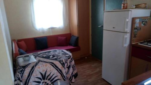 a small room with a red couch and a refrigerator at MOBILHOME 4/5 P /GORGES DU VERDON / TOUT EQUIPE / / TOUT CONFORT / REFAIT A NEUF / LAC DE STE CROIX A PROXIMITE in Sainte-Croix-de-Verdon