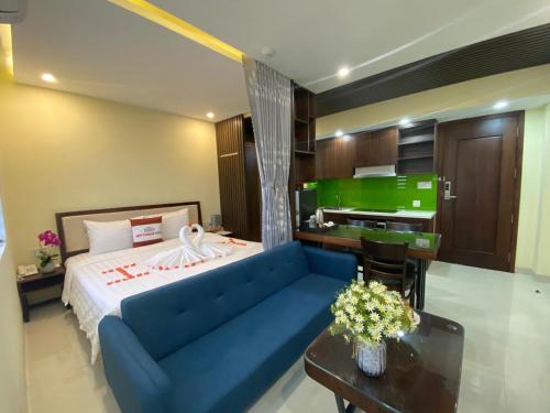 a bedroom with a blue couch and a kitchen at New Tourane Hotel in Danang