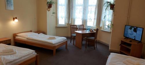 Habitación con 2 camas, mesa y TV. en Hotel Wanda en Kętrzyn