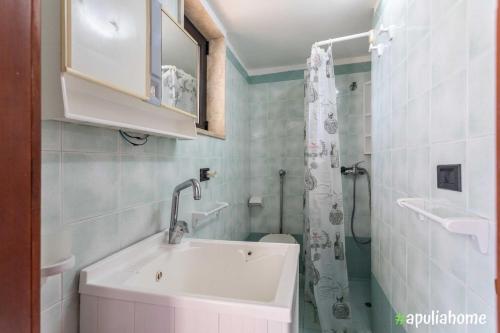 La salle de bains blanche est pourvue d'un lavabo et d'une douche. dans l'établissement Emma's Villa fronte mare con piscina, à Torre Suda