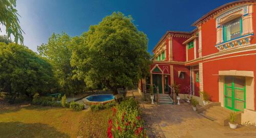 a red house with a swimming pool in front of it at WelcomHeritage Judges Court in Kangra