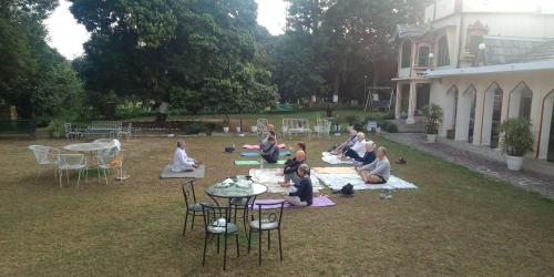 a group of people sitting on the grass in a yard at WelcomHeritage Judges Court in Kangra