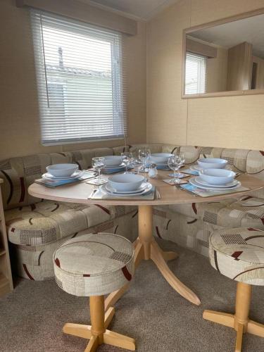 a dining room table with plates and wine glasses at Comfy 2 bed holiday caravan in Whitstable