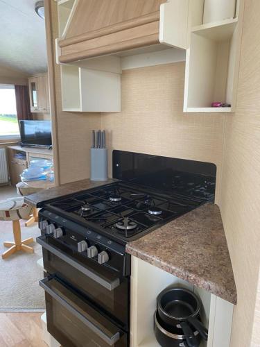 a kitchen with a stove and a counter top at Comfy 2 bed holiday caravan in Whitstable