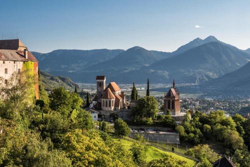 a town on a hill with mountains in the background at Gartenheim App Franz in Schenna
