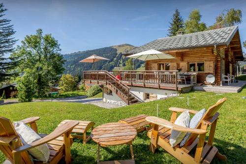 a group of chairs sitting in the grass in front of a log cabin at Chalet Joux Verte - OVO Network in Les Gets