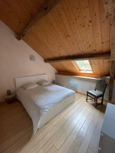 une chambre avec un lit et une chaise dans un grenier dans l'établissement Le Moulin de Cherré gîte vert, à Aubigné-Racan