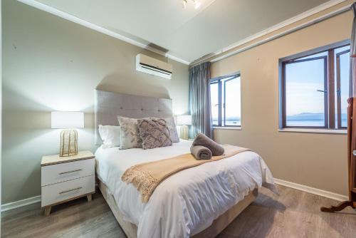 um quarto com uma cama grande e 2 janelas em Beacon Wharf , George Hay 6 Seafront Accommodation em Mossel Bay