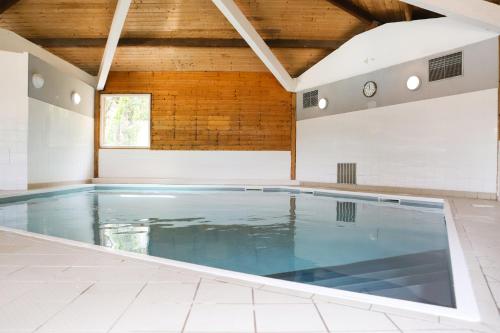 a swimming pool in a house with a wooden ceiling at Olydea Oleron les Sables Vignier in Saint-Georges-dʼOléron