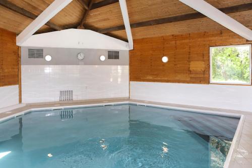 a swimming pool in a house with a wooden ceiling at Olydea Oleron les Sables Vignier in Saint-Georges-dʼOléron