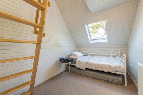 a small attic bedroom with a bed and a window at Nether Newton - Sleeps 10, Hottub, Sauna, Private Garden in Newmilns