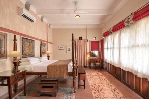 a bedroom with a bed and a desk and a window at Neemrana Fort-Palace in Neemrana