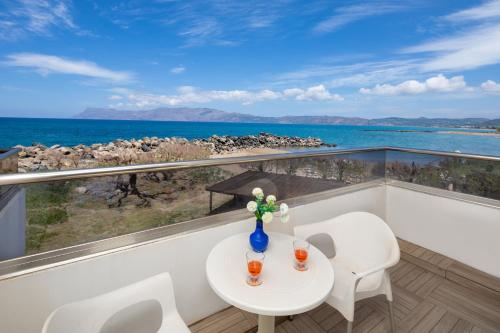 a balcony with a table and chairs and the ocean at Elena Beach Hotel in Kissamos