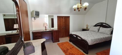 Schlafzimmer mit einem Bett, einem Schreibtisch und einem Spiegel in der Unterkunft BBL APARTAMENTOS - B in Nazaré