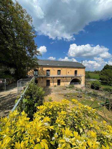 un bâtiment avec des fleurs jaunes devant lui dans l'établissement Le Moulin de cherré gîte bleu, à Aubigné-Racan