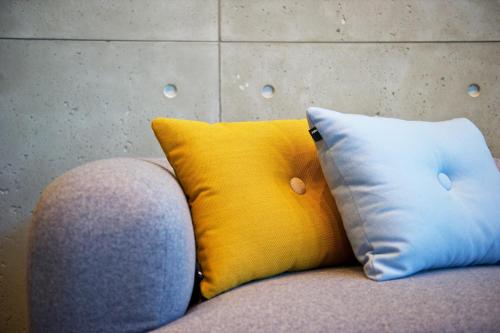 a yellow pillow and two white pillows on a couch at Staycity Aparthotels Manchester Piccadilly in Manchester
