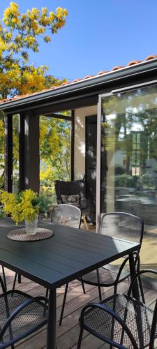 - une table et des chaises noires sur la terrasse dans l'établissement Maison "Les Agathines", à Ronce-les-Bains