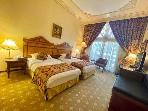 um quarto de hotel com duas camas e uma televisão em Serenada Golden Palace - Boutique Hotel em Beirute