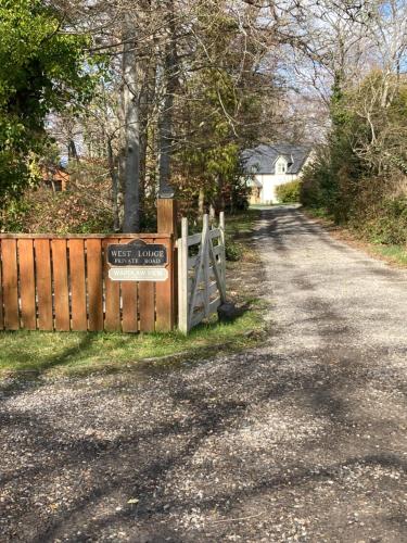 a fence with a sign on it next to a road at 'Wardlaw View' Luxury studio apartment with stunning view in Kirkhill