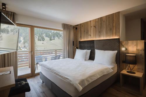 a bedroom with a large bed and a large window at Hotel Andermax in San Candido