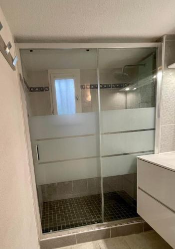 une douche avec une porte vitrée dans une salle de bain dans l'établissement Pavillon à 400m de la plage avec piscine, à Valras-Plage