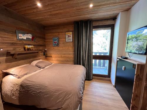 une chambre avec un lit et une télévision dans l'établissement OURS BLANC 29 duplex avec vue, à La Clusaz