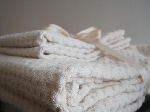 a stack of white towels with a pair of scissors on top at B&B Porto Del Bivio in Duino